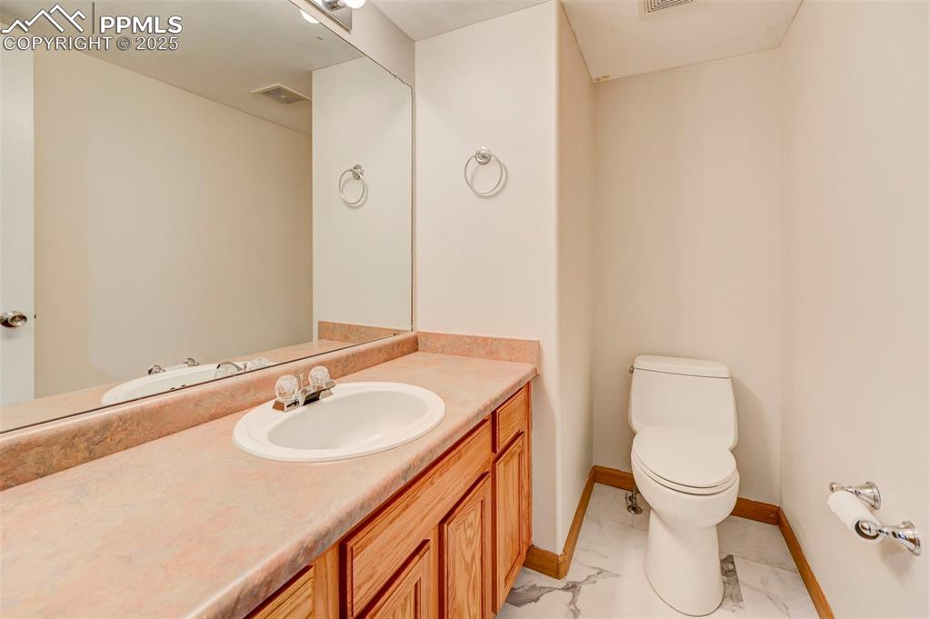 Image 12 of 34: Half bathroom with vanity and marble finish flooring