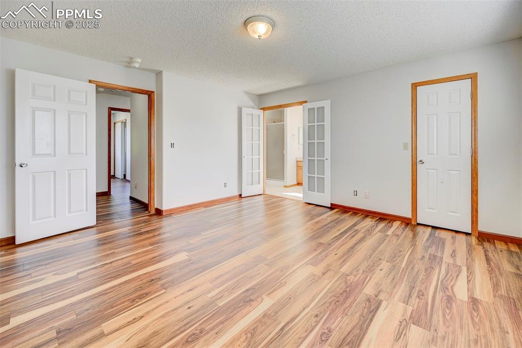 Image 20 of 34: Unfurnished bedroom with light wood-style flooring, a textured ceiling, and