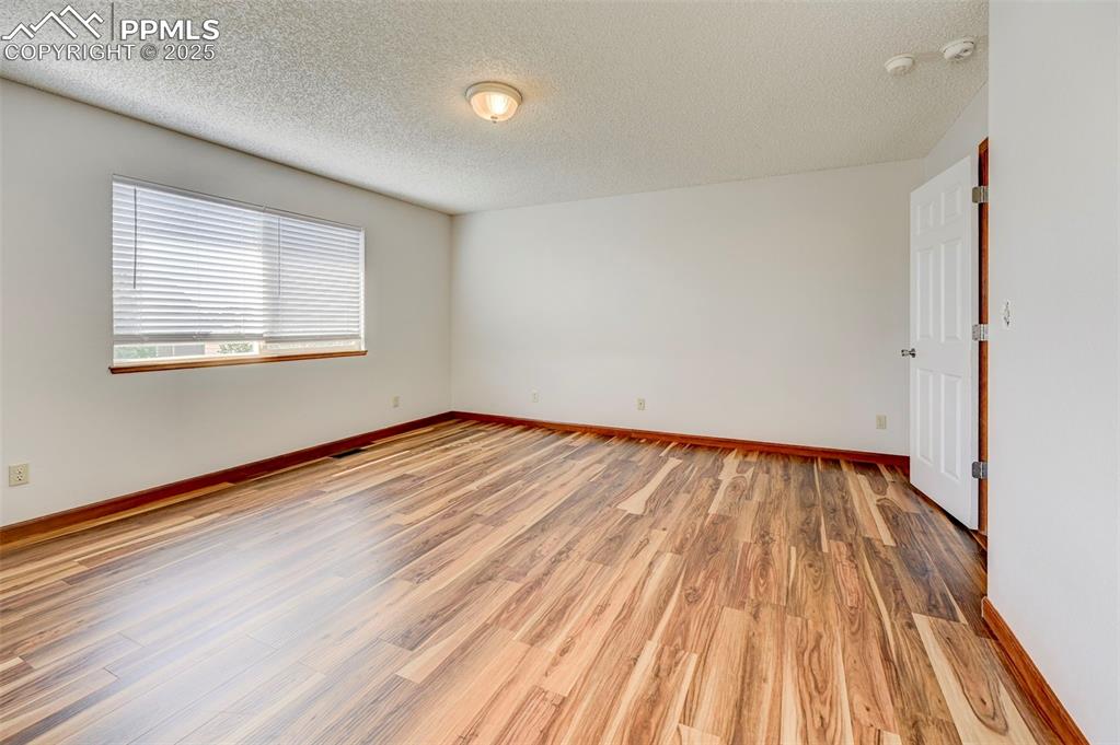 Image 24 of 34: Spare room featuring light wood finished floors, a textured ceiling, and a 