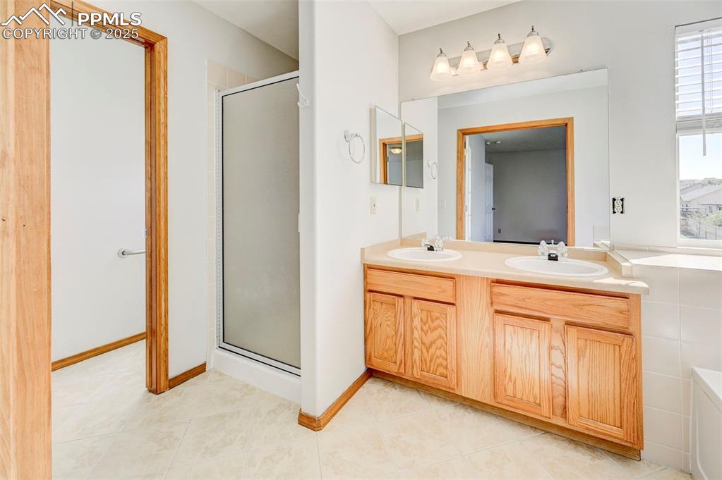 Image 25 of 34: Bathroom featuring a stall shower, double vanity, and tile patterned floori
