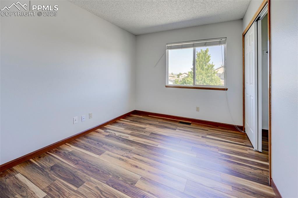Image 26 of 34: Unfurnished bedroom featuring a textured ceiling, wood finished floors, and