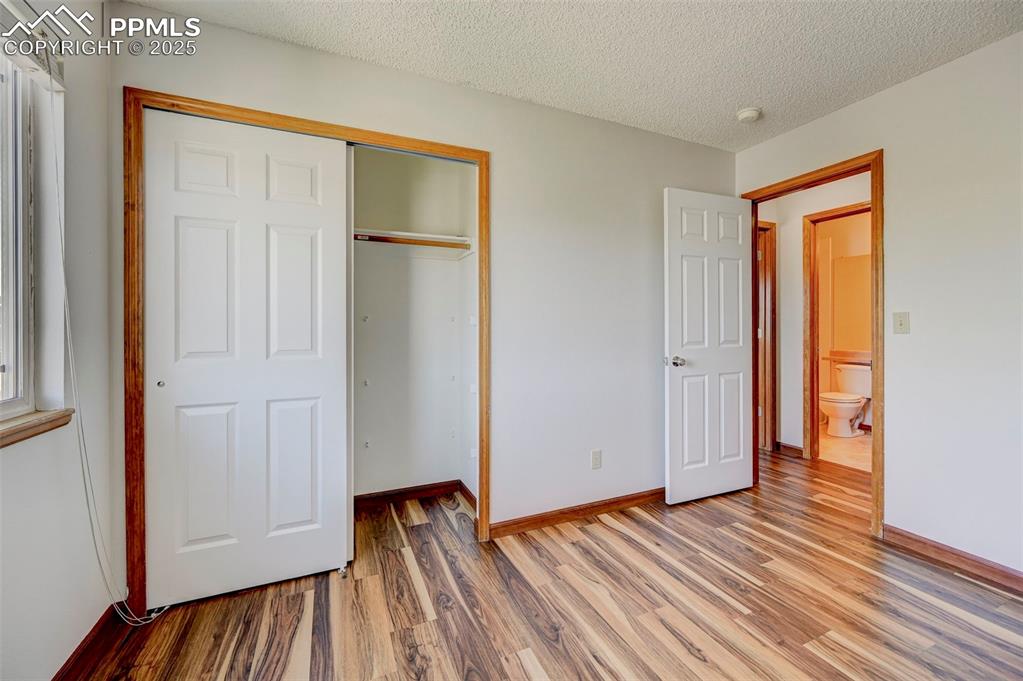 Image 27 of 34: Unfurnished bedroom with light wood finished floors, a closet, and a textur