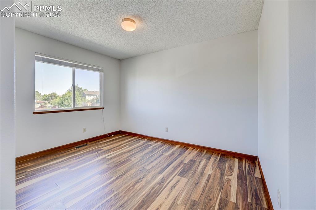 Image 29 of 34: Unfurnished room featuring wood finished floors and a textured ceiling