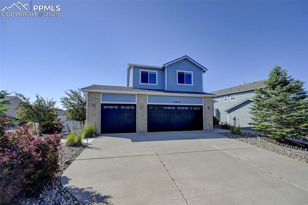 Image 3 of 34: View of front of house with brick siding, concrete driveway, and an attache