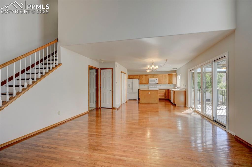 Image 5 of 34: Unfurnished living room with a chandelier, light wood-style floors, and sta