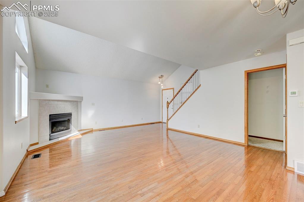 Image 6 of 34: Unfurnished living room with light wood-type flooring, a fireplace, a chand