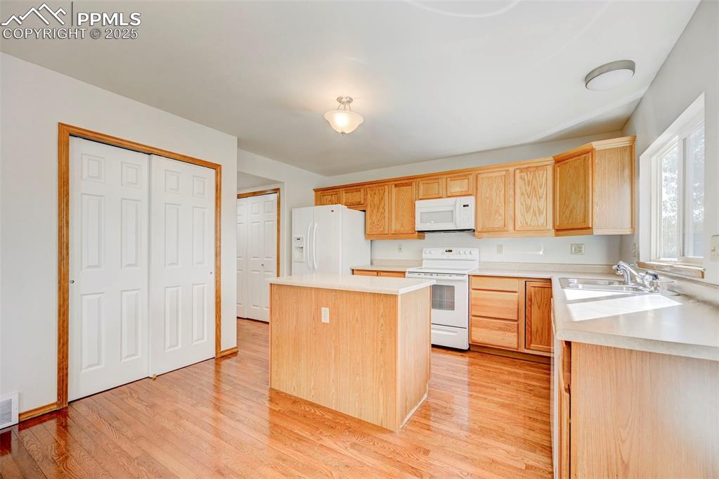 Image 9 of 34: Kitchen with white appliances, a kitchen island, light wood-style flooring,
