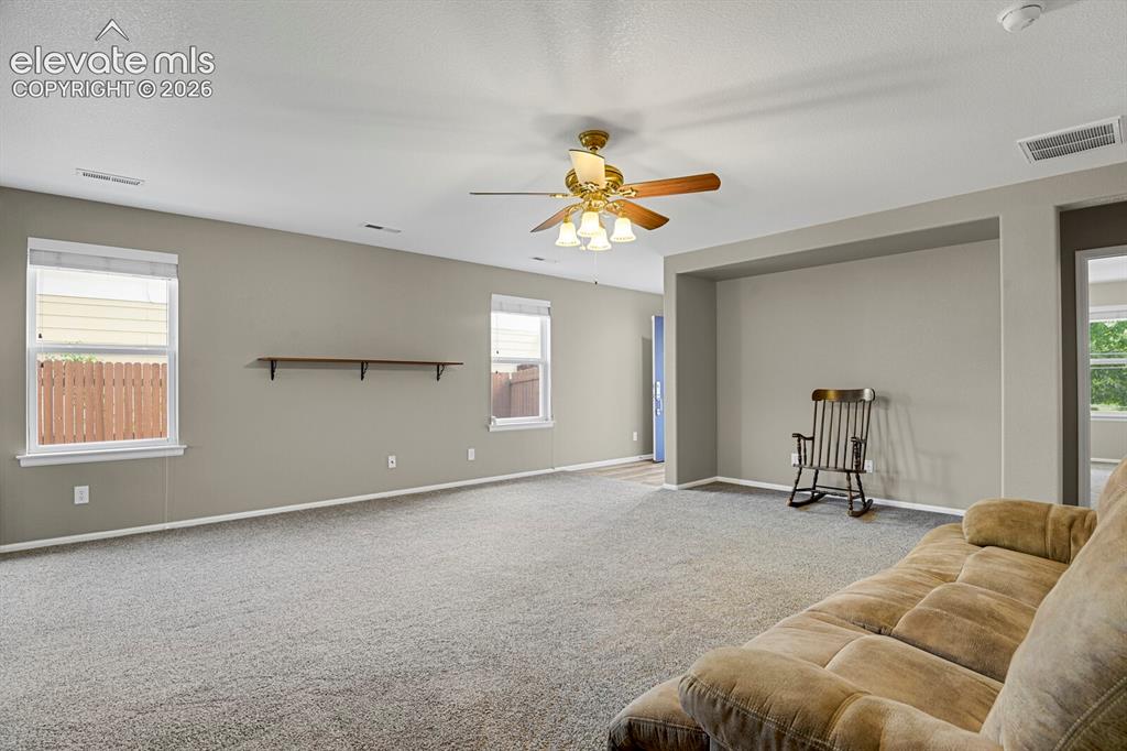 Image 10 of 31: Spacious living room featuring neutral-toned walls, gray carpeting and a ce