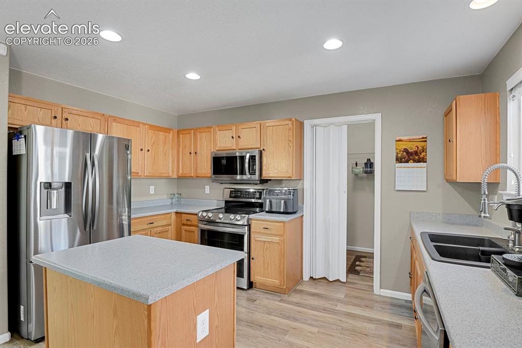 Image 16 of 31: Kitchen with light wood cabinetry, island and a stainless steel dishwasher