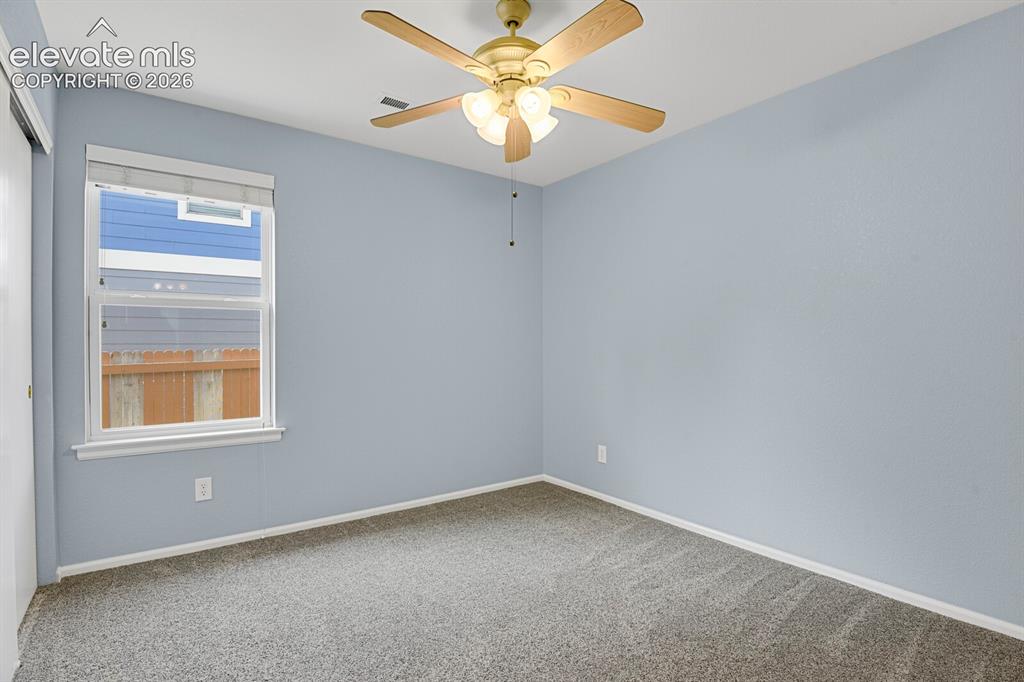 Image 21 of 31: Carpeted bedroom featuring a ceiling fan with integrated lighting, two wind