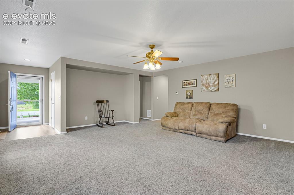 Image 9 of 31: Open-concept living room area with neutral gray walls and gray carpeting