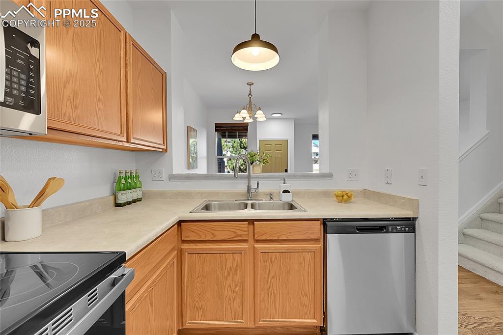 Image 11 of 31: Kitchen with stainless steel appliances, decorative light fixtures, light c