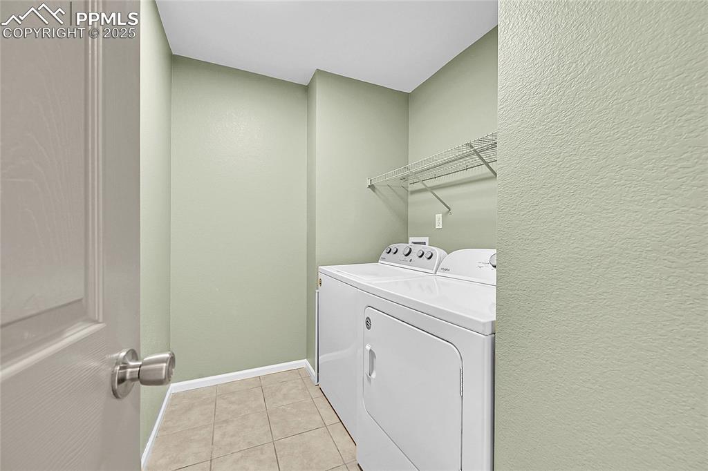Image 16 of 31: Washroom with light tile patterned floors, washer and clothes dryer, and a 