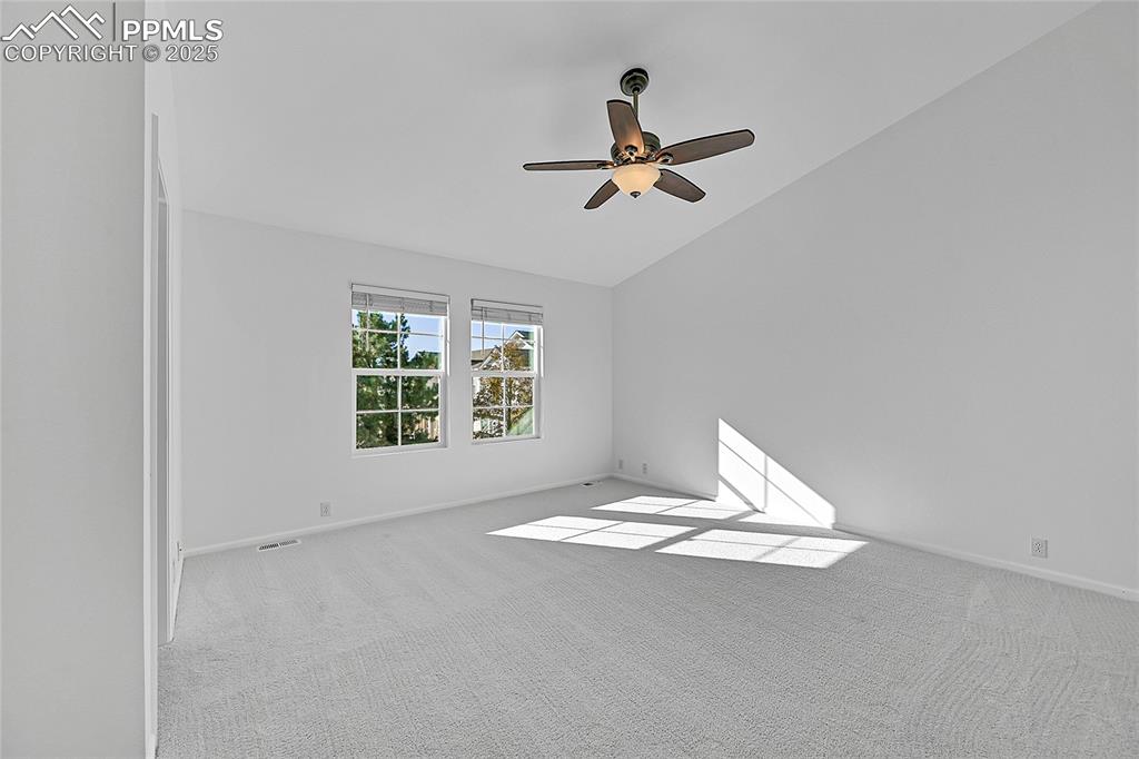 Image 21 of 31: Carpeted spare room with vaulted ceiling and a ceiling fan