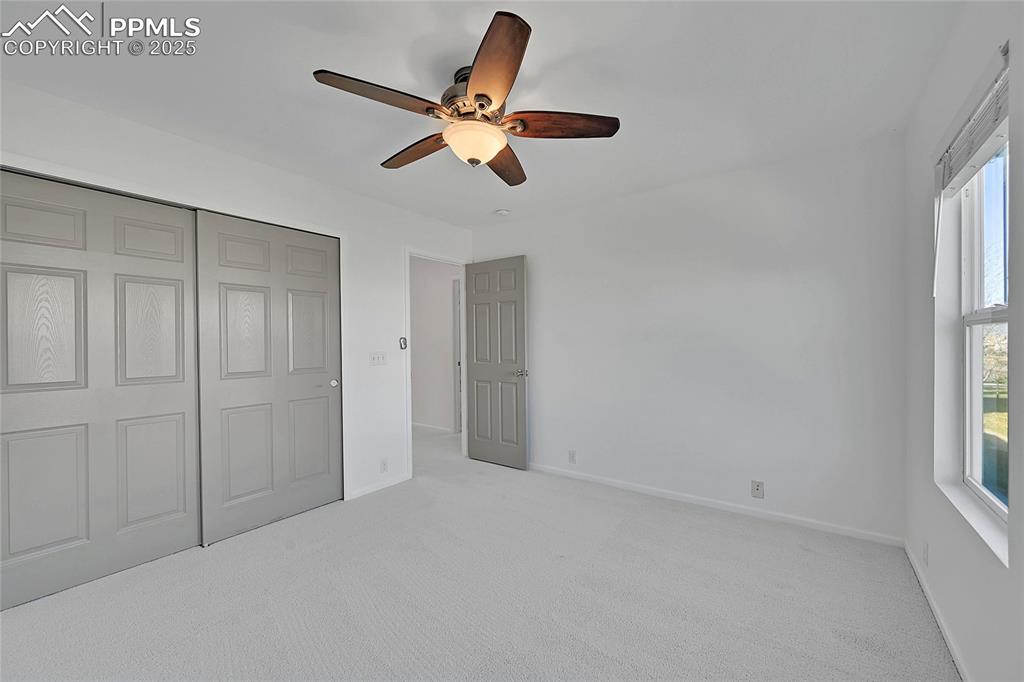 Image 24 of 31: Unfurnished bedroom with light colored carpet, ceiling fan, and a closet