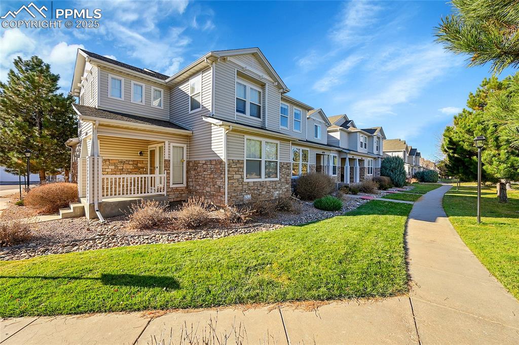 Image 25 of 31: Traditional-style house with a porch, stone siding, and a front yard