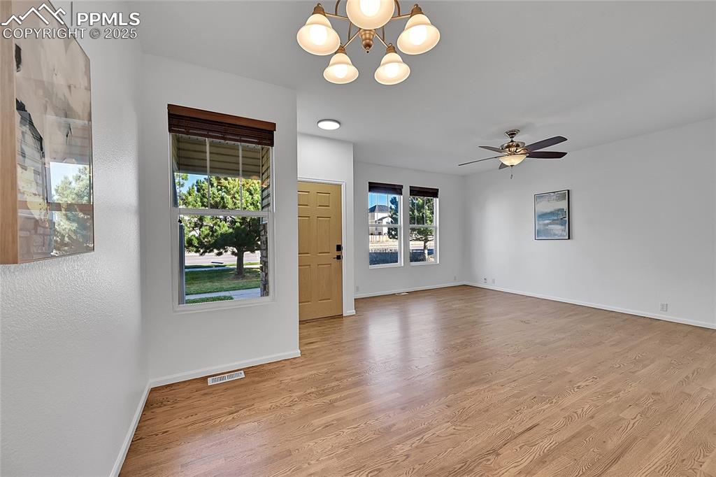 Image 6 of 31: Empty room with light wood-style floors, a chandelier, and ceiling fan