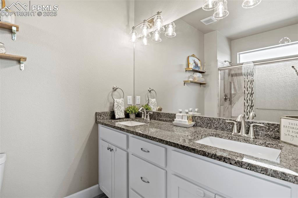 Image 28 of 30: Full bath with double vanity, a stall shower, and toilet