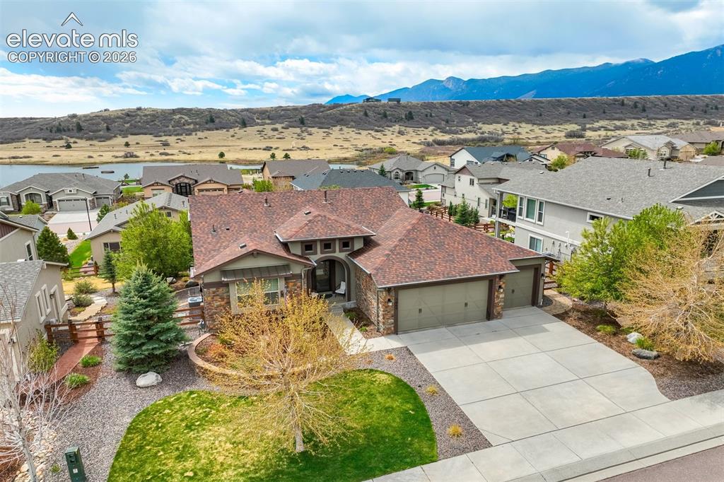 Caption: Contemporary residence featuring a multi-tone shingle roof, stone and stucco exterior, and a two-car