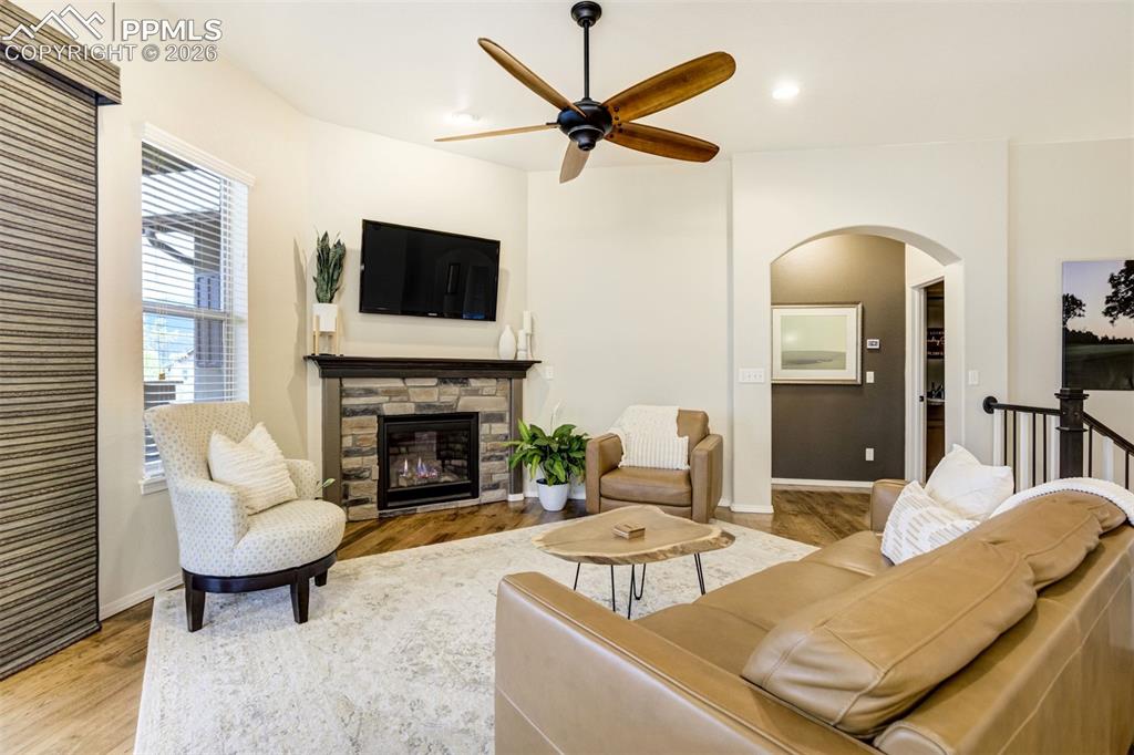 Image 10 of 48: Living area featuring wood-finish flooring, a stone-faced fireplace with a