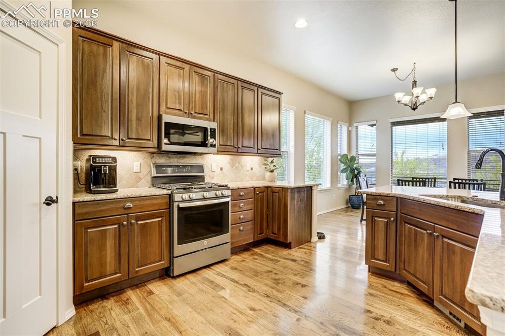 Image 14 of 48: Kitchen featuring hardwood flooring, rich wood cabinetry, stainless steel a
