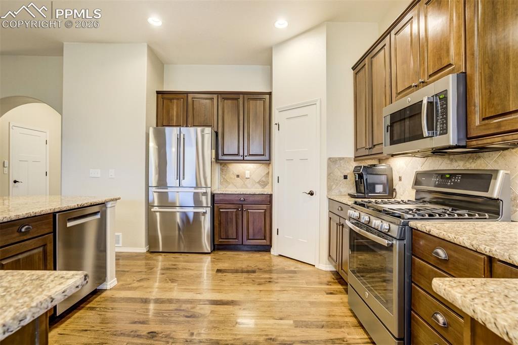 Image 15 of 48: Kitchen featuring hardwood flooring, stainless steel appliances, dark wood
