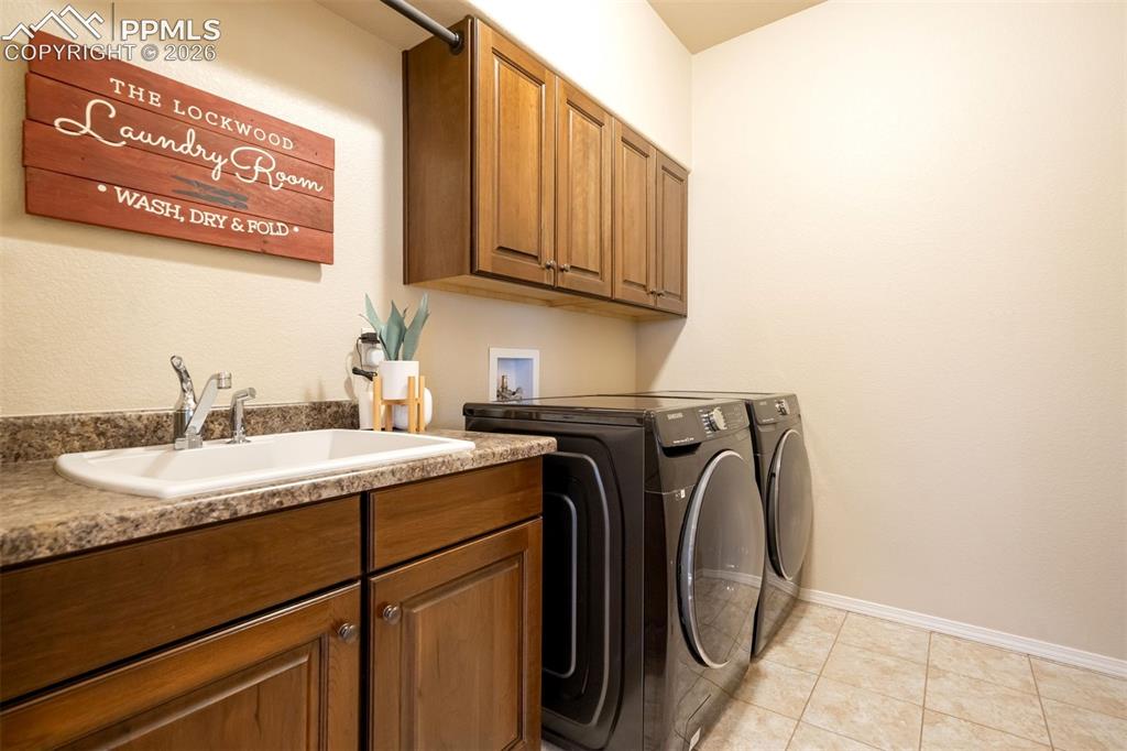 Image 24 of 48: Utility room featuring a built-in sink with a chrome faucet, wood-finish ca
