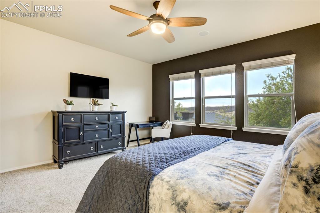 Image 27 of 48: Bedroom featuring three large windows, a ceiling fan with integrated lighti