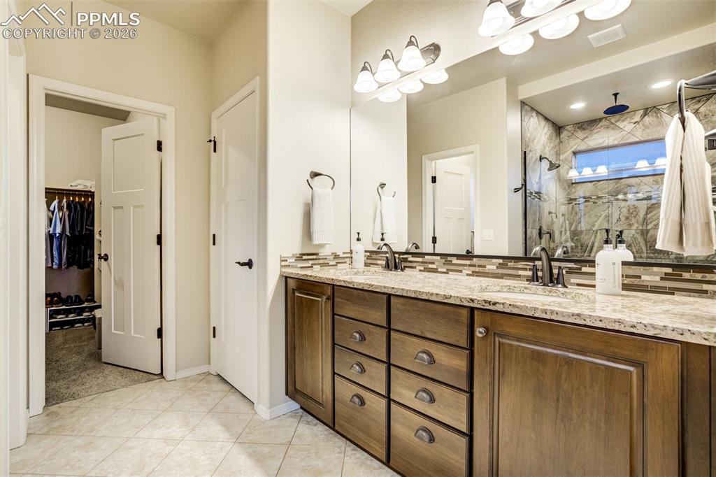 Image 29 of 48: Double vanity with stone countertop, dual undermount sinks, and bronze-fini