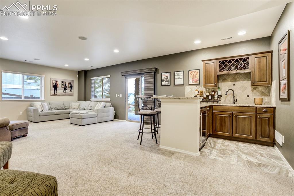 Image 34 of 48: Spacious recreation area featuring a built-in wet bar with wood cabinetry,
