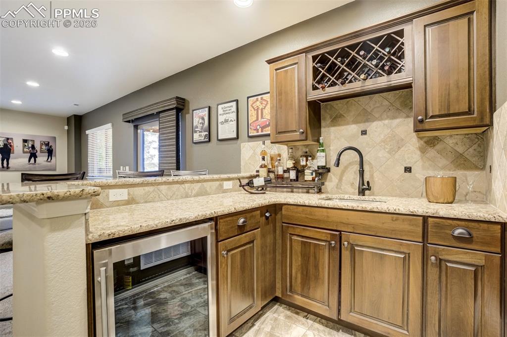 Image 35 of 48: Built-in wet bar featuring a stainless steel beverage refrigerator, stone c