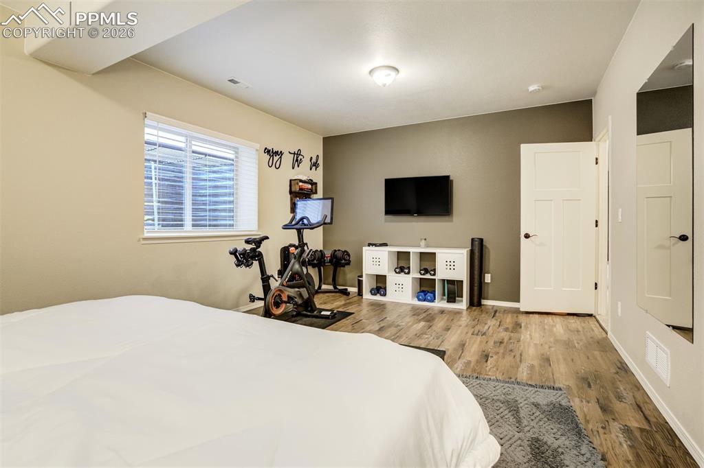 Image 40 of 48: Spacious basement room 3 featuring wood-finish flooring and a window with b