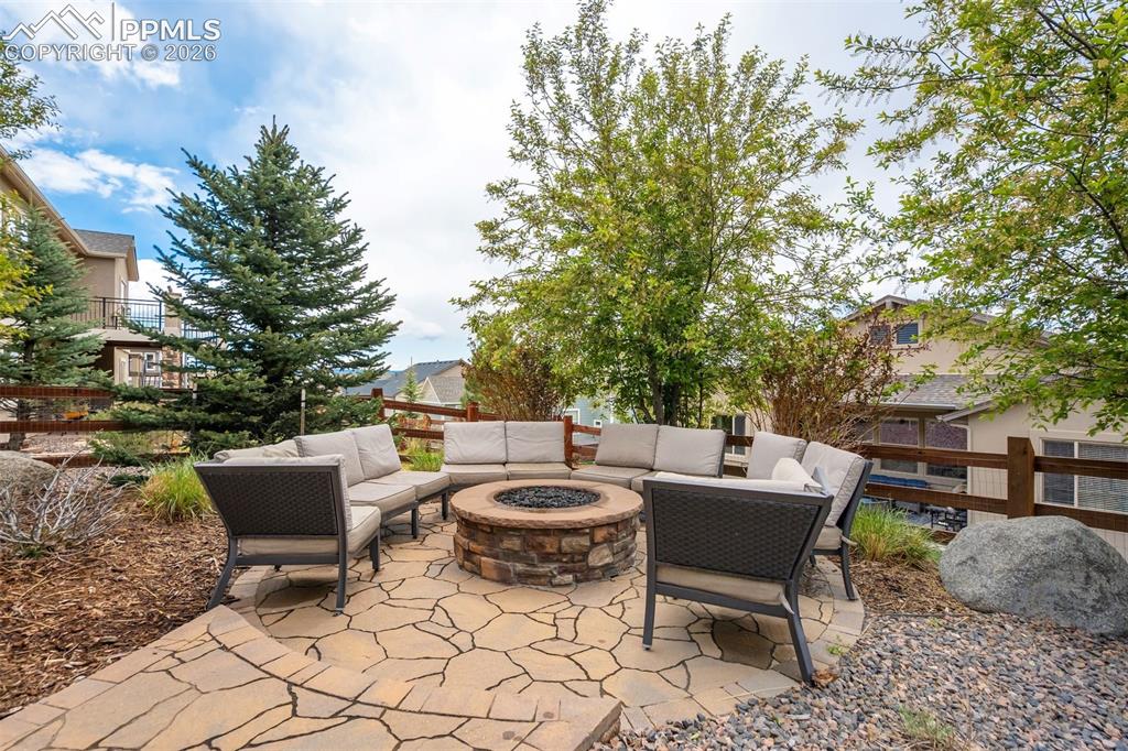 Image 45 of 48: Flagstone patio featuring a built-in stone fire pit, surrounded by lush lan