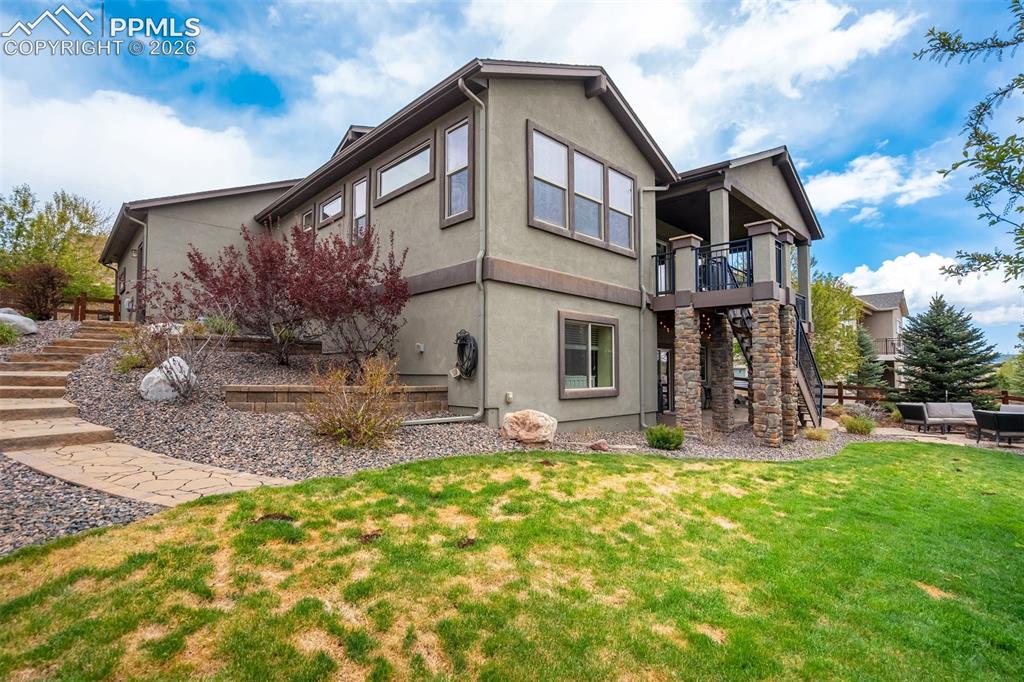 Image 46 of 48: Terraced landscaping with a stone pathway, a two-story exterior with stucco