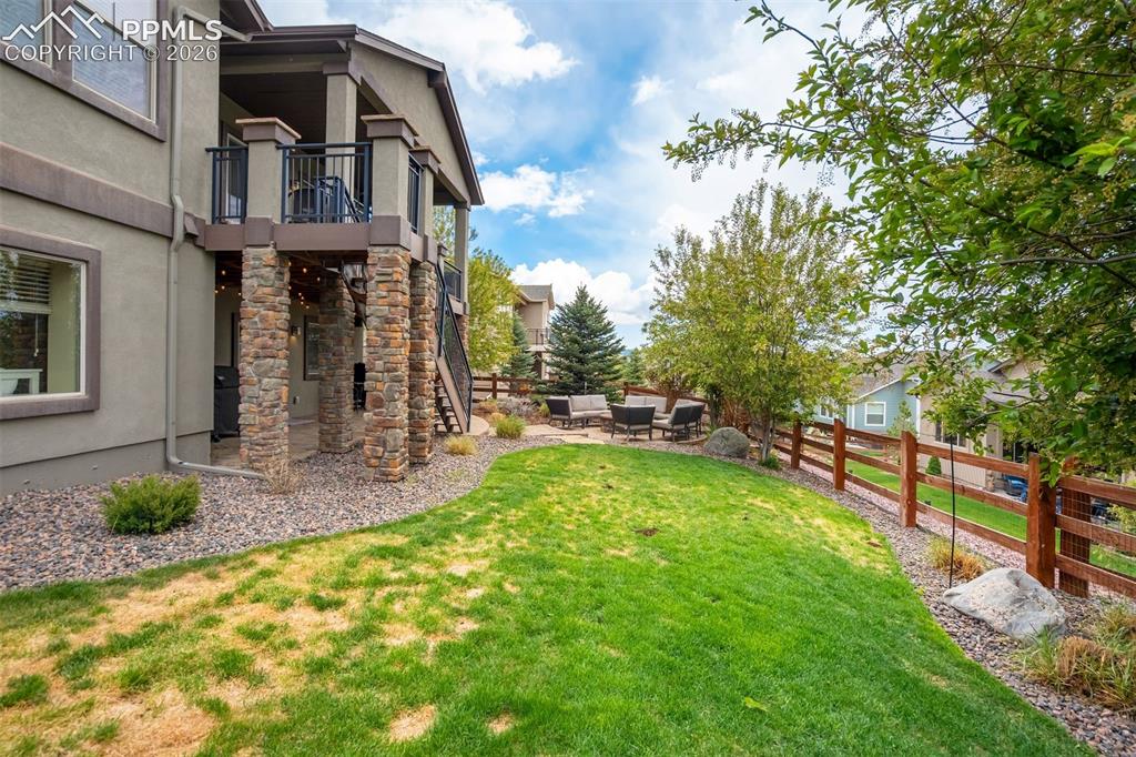 Image 48 of 48: Rear exterior featuring a stone-clad patio supporting an upper-level balcon