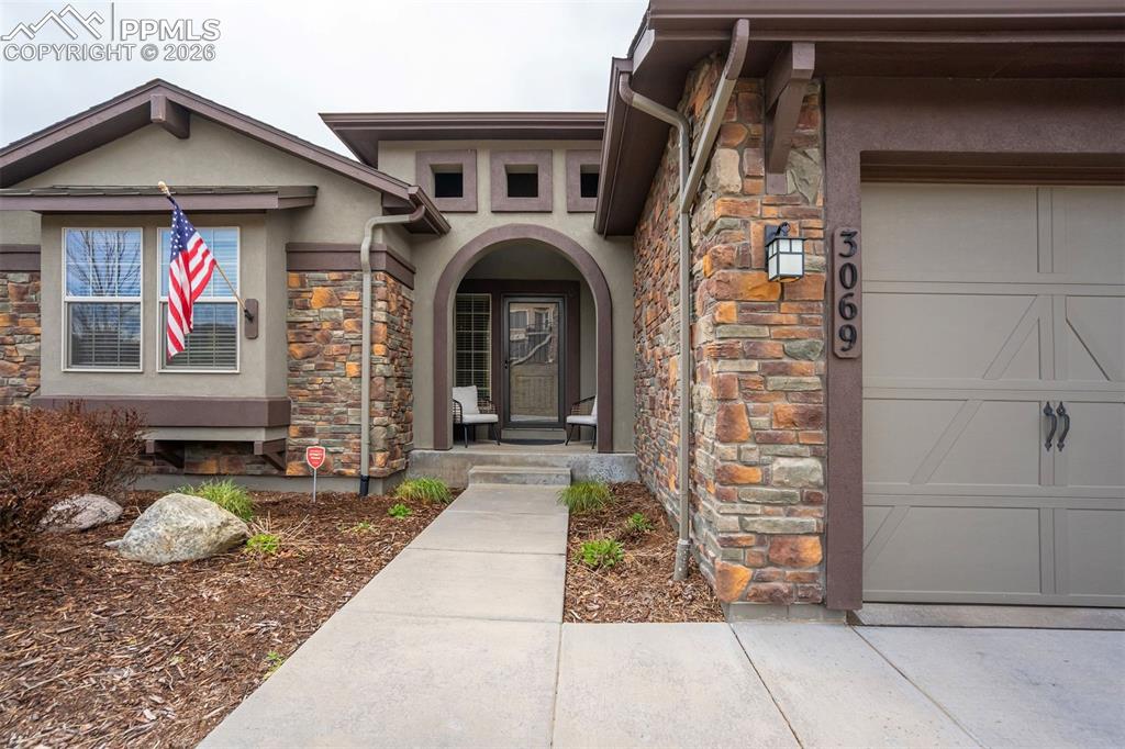 Image 7 of 48: Exterior featuring stone accents, stucco siding, an arched entryway, an att