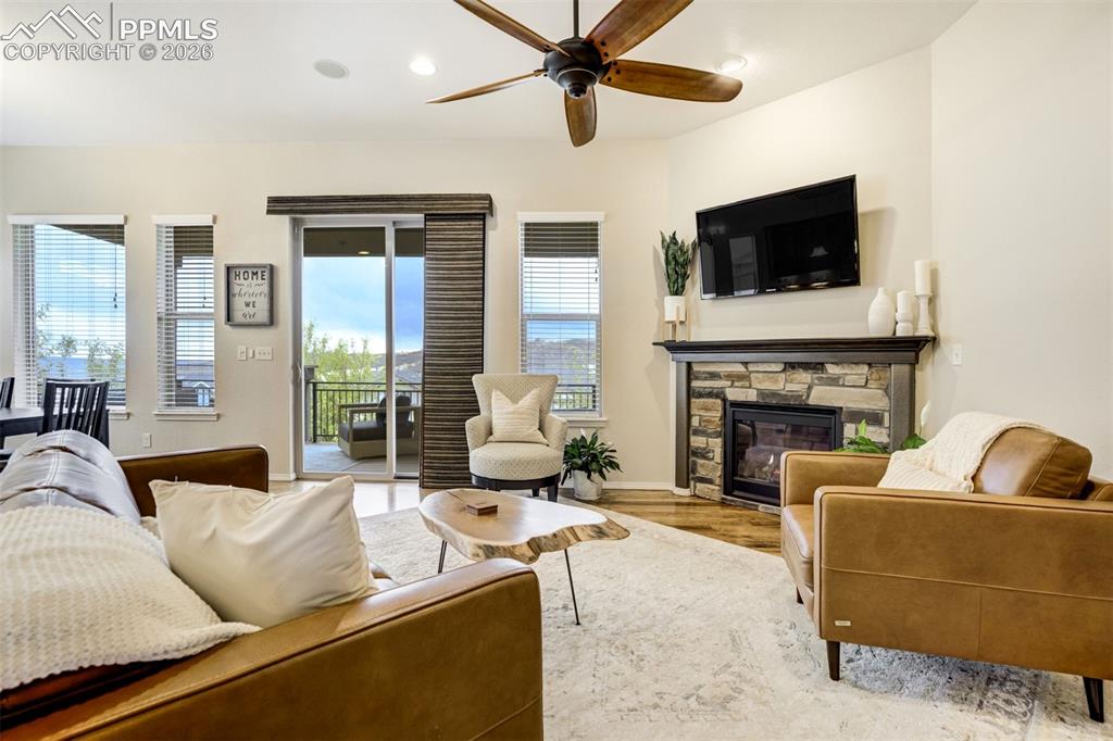 Image 9 of 48: Living area featuring a stacked stone fireplace with a dark wood mantle, wo