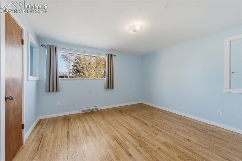 Image 12 of 38: Spare room featuring wood floors and baseboards