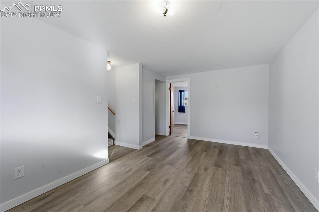 Image 18 of 38: Empty room featuring wood finished floors and stairway