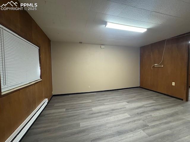 Image 14 of 19: Empty room featuring a baseboard radiator, light wood-style floors, and woo