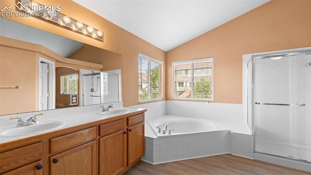 Image 20 of 50: Bathroom with lofted ceiling, a shower stall, light wood-style floors, a ba