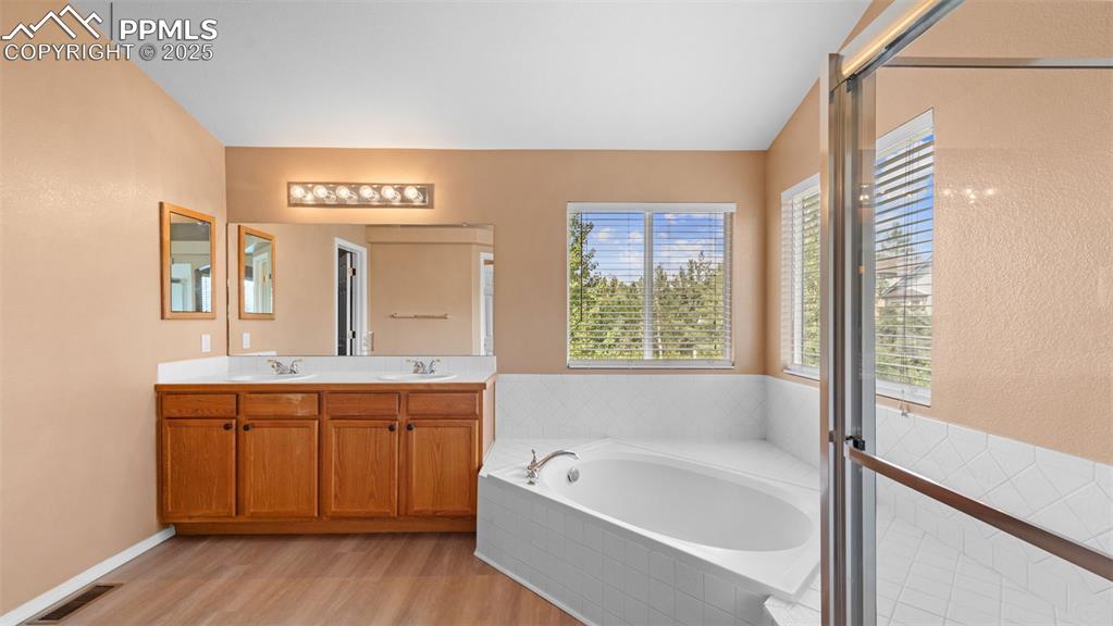 Image 21 of 50: Full bath with a garden tub, double vanity, and light wood finished floors