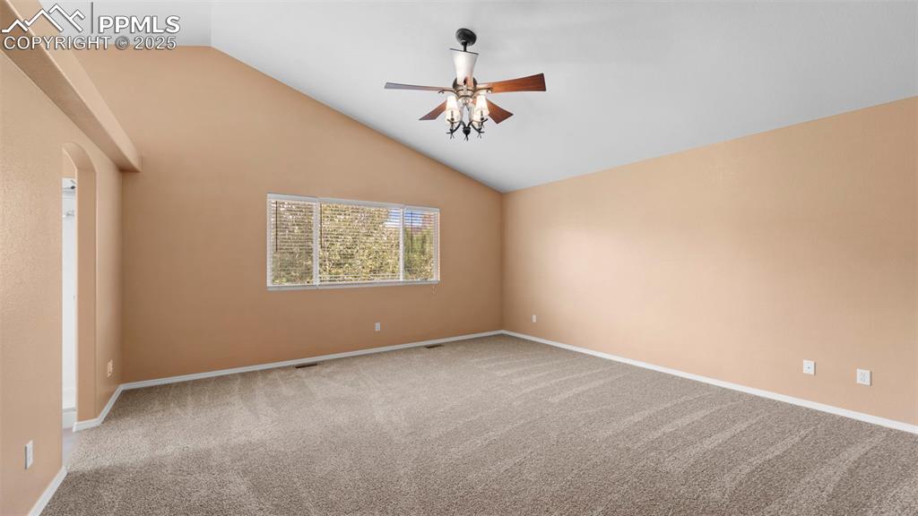 Image 22 of 50: Empty room featuring vaulted ceiling, light carpet, ceiling fan, and arched