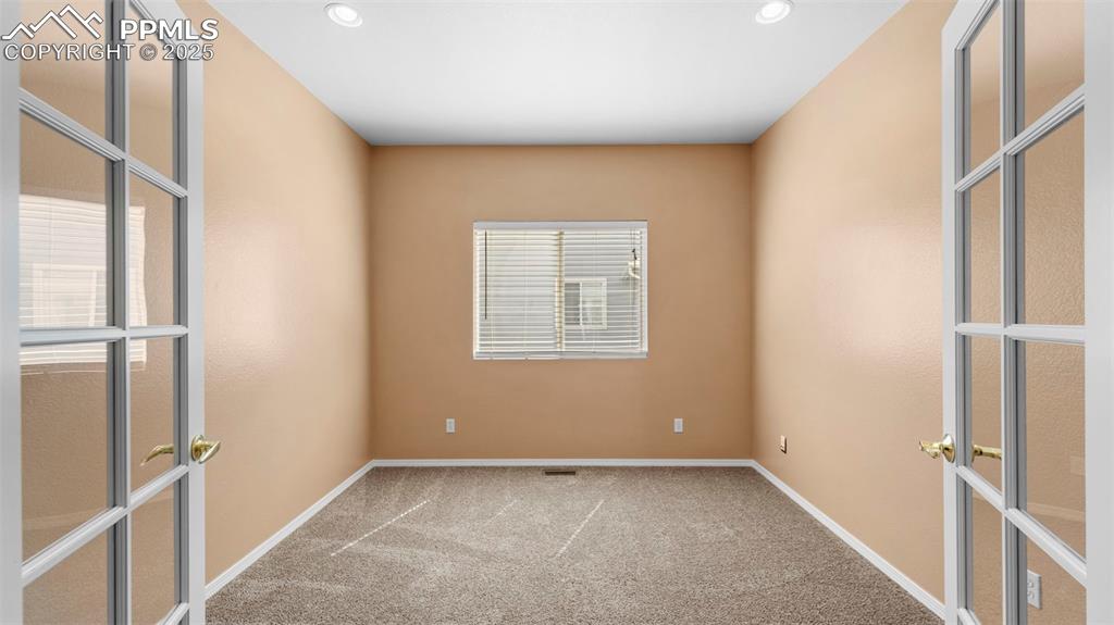 Image 23 of 50: Spare room with french doors, light colored carpet, and recessed lighting