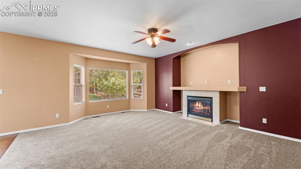 Image 25 of 50: Unfurnished living room featuring a tile fireplace, carpet, and a ceiling f