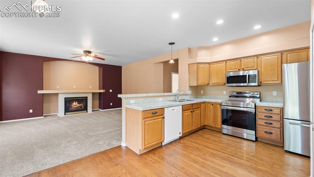 Image 26 of 50: Kitchen featuring appliances, hanging light fixtures, light countertops, a