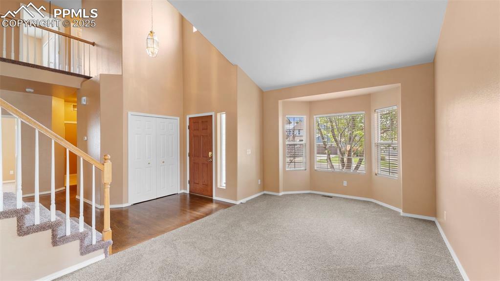 Image 30 of 50: Foyer entrance with plenty of natural light, carpet floors, high vaulted ce