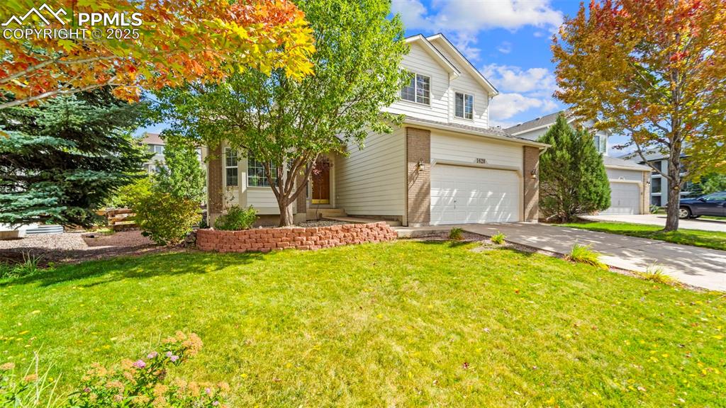Image 4 of 50: Vew of property with brick siding, a front yard, driveway, and a garage