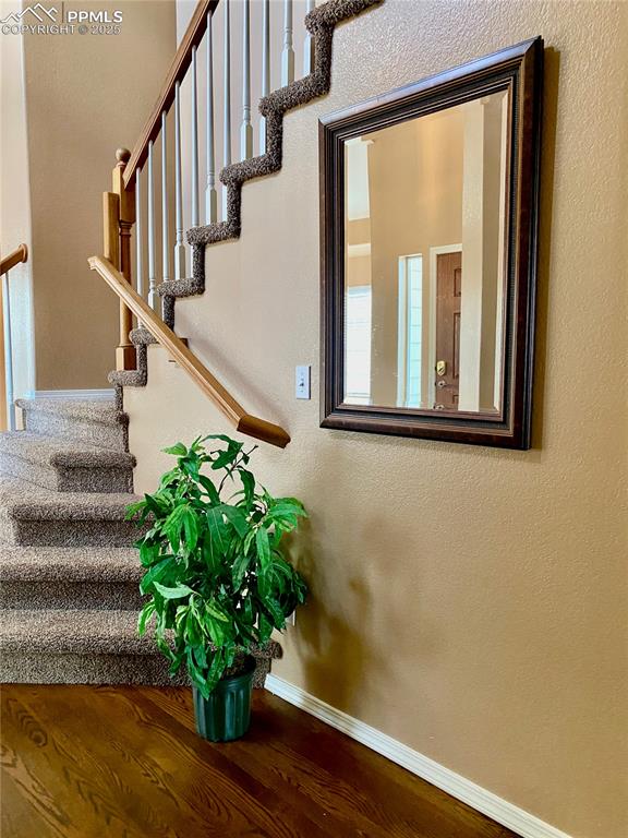 Image 44 of 50: Staircase with wood finished floors and a textured wall