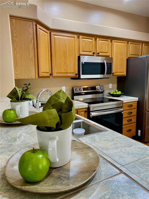 Image 49 of 50: Kitchen with appliances with stainless steel finishes and tile counters